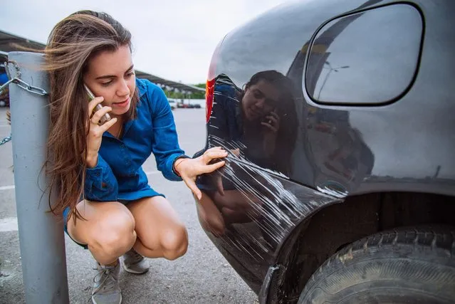 Sad woman standing near car with scratch on parking and talking by the phone. (Photo by Vera Petrunina/Getty Images)