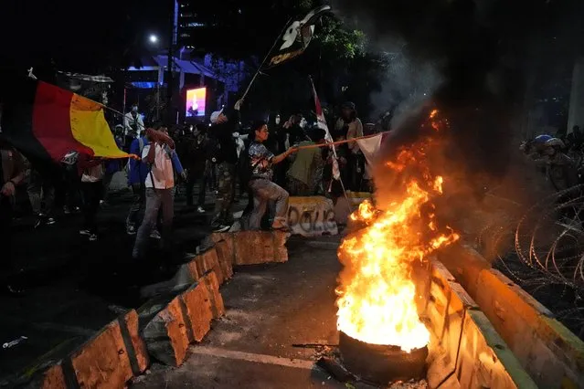 Student protesters wave flags as they burn a tire during a rally demanding that the government revoke its decision to raise fuel prices in Jakarta, Indonesia, Tuesday, September 13, 2022. Prices of gasoline and diesel fuel jumped by about 30% earlier this month after President Joko Widodo's administration cut fuel subsidies to reduce the country's multibillion-dollar budget deficit. (Photo by Dita Alangkara/AP Photo)
