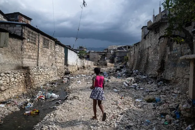 A girl walks on the banks of a stream filled with trash in Port-au-Prince, Haiti on October 13, 2022. (Photo by Ricardo Arduengo/Reuters)