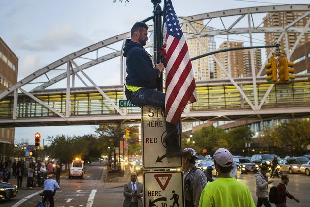 A man places a U.S. flag in memory of the victims of the recent truck attack on the bike path near the crime scene Thursday, November 2, 2017, in New York. A man in a rented pickup truck mowed down pedestrians and cyclists along the busy bike path near the World Trade Center memorial on Tuesday, killing at least eight people and seriously injuring others in what the mayor called “a particularly cowardly act of terror”. (Photo by Andres Kudacki/AP Photo)
