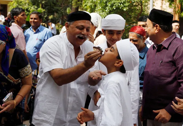 A man offers a pastry to a kid at a fire temple during the Parsi New Year celebrations in Ahmedabad, India, August 17, 2016. (Photo by Amit Dave/Reuters)