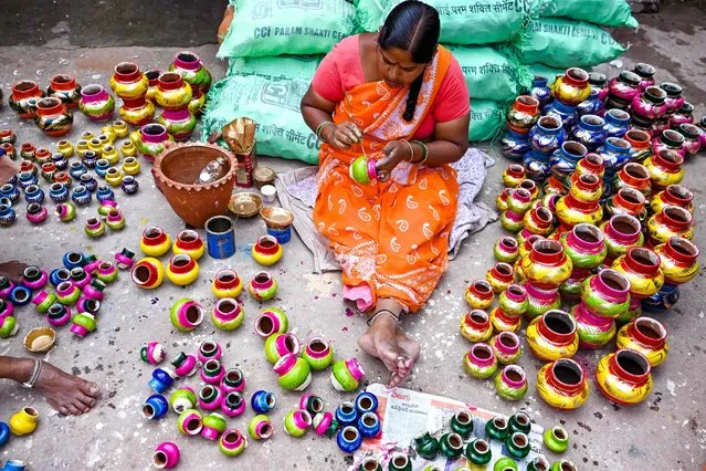 A potter paints earthen pots ahead of the Hindu festival of Diwali, at a workshop in Hyderabad on October 20, 2022. (Photo by Noah Seelam/AFP Photo)