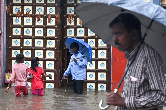 People make their way through a flooded street during a heavy monsoon rainfall in Chennai on November 1, 2022. (Photo by Arun Sankar/AFP Photo)