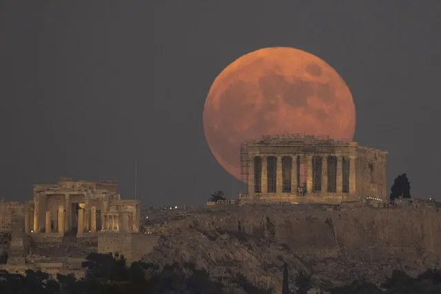 The Full Moon rises behind the Acropolis hill and the ancient Parthenon Temple, in Athens, on Tuesday, November 8, 2022. (Photo by Petros Giannakouris/AP Photo)
