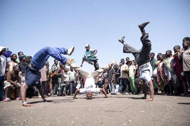 A crowd gathers to watch breakdancers from the Congo Street collective perform at the Kituku market port in Goma on April 3, 2025. Drawing inspiration from breakdance and hip-hop, while incorporating their unique style, the collective's transform these space into a vibrant stage, captivating the audience with their energy and mastery of urban dance. (Photo by Jospin Mwisha/AFP Photo)