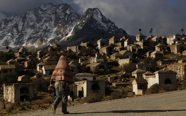 In this Oct. 14, 2014, photo, a woman walks by the Milluni cemetery at the base of the Huayna Potosi Mountain on the outskirts of El Alto, Bolivia. The cemetery was built in 1965 to bury dozens of miners who were killed, allegedly by soldiers, during the military dictatorship of President Rene Barrientos. Today, the cemetery is used to bury the family members of those miners. (AP Photo/Juan Karita)