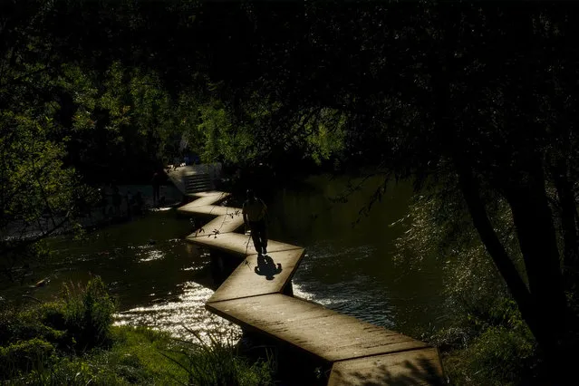 A man crosses a walkway over the Arga River as the sun sets at the end of a summer day, in Pamplona northern Spain, Wednesday, July 27, 2016. (Photo by Alvaro Barrientos/AP Photo)