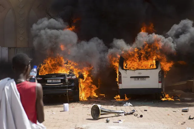 A man watches cars burn at a hotel where members of the parliament were said to be staying in Ouagadougou, capital of Burkina Faso, October 30, 2014. (Photo by Joe Penney/Reuters)