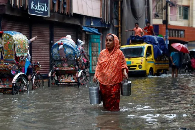 A woman carries tiffin carriers as she walks through a water-logged street after heavy rain in Dhaka, Bangladesh, July 21, 2020. (Photo by Mohammad Ponir Hossain/Reuters)