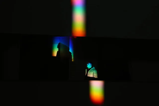 A visitor walks through a rainbow created by prisms at the Smithsonian National Museum of the American Indian on Friday December 30, 2022 in Washington, DC. The rainbow pattern created by the prisms moves around the building depending on the time of the year and the direction of the sun. (Photo by Matt McClain/The Washington Post)