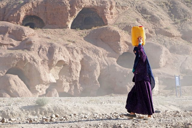 An Afghan Hazara woman carries a plastic container filled with drinking water as she walks back home in Bamiyan, Afghanistan, on June 18, 2025. (Photo by Mohammad Faisal Naweed/AFP Photo)