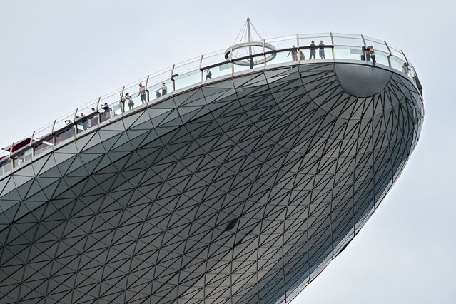 People stand on the observation deck of the Marina Bay Sands Hotel in Singapore on May 23, 2024. (Photo by Roslan Rahman/AFP Photo)