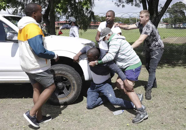 Members of the leftist opposition party Economic Freedom Fighters are attacked while protesting outside the Brackenfell High School, near Cape Town, South Africa, Monday, November 9, 2020. South African president Cyril Ramaphosa has called for restraint following clashes at an anti-racism protest outside a school in Cape Town. Members of the leftist opposition party Economic Freedom Fighters protested in front of the Brackenfell High School over allegations that a graduation event was attended only by white pupils. (Photo by AP Photo/Stringer)