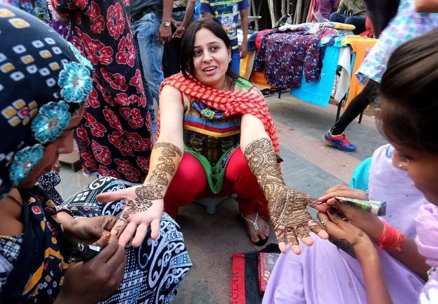A picture made available on 30 October 2015 shows Indian married women getting their hands and arms decorated with henna during the eve of the Karva Chauth festival at a roadside in Bhopal, India, 29 October 2015. Married Hindu women observed fasting and praying for the longevity and wellbeing of their husbands. Karva Chauth festival will be observed on 30 October this year. (Photo by Sanjeev Gupta/EPA)