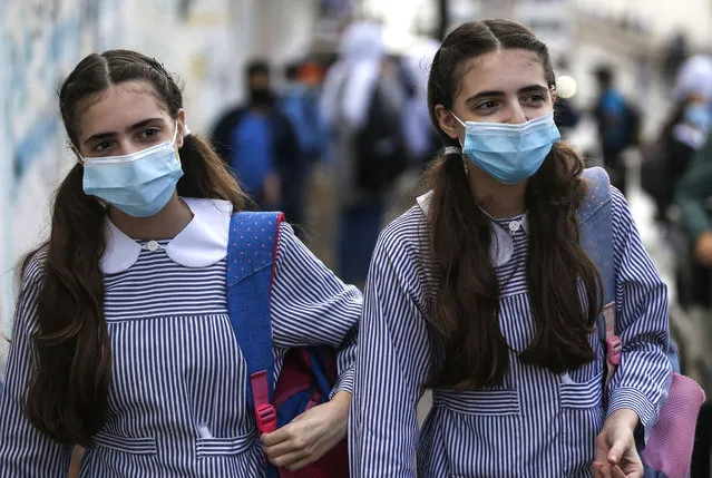 Twin Palestinian girls wearing protective face masks due to the COVID-19 pandemic walk back home from their UN school in Gaza City on November 3, 2020. (Photo by Mohammed Abed/AFP Photo)