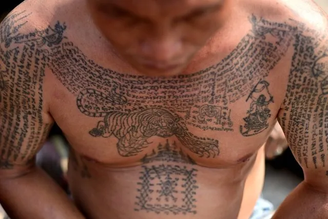 A Buddhist devotee with a traditional “Sak Yant” tattoo offers prayers during an annual sacred tattoo festival at the Wat Bang Phra temple in Nakhon Pathom province on March 4, 2023. (Photo by Manan Vatsyayana/AFP Photo)