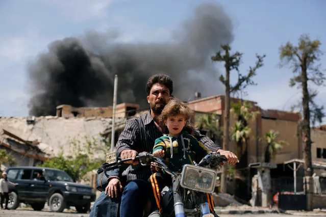 A man and a boy ride a motorbike at the city of Douma in Damascus, Syria, April 16, 2018. (Photo by Omar Sanadiki/Reuters)