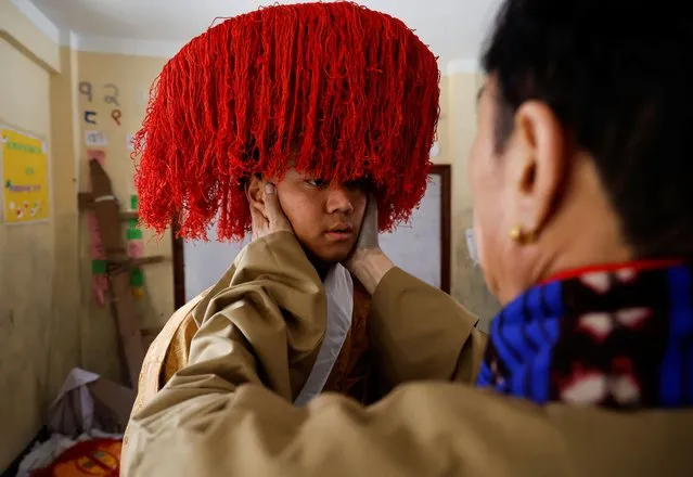 A Tibetan man wearing a traditional headgear gets help ahead of the function organized to mark “Losar” or the Tibetan New Year in Kathmandu, Nepal on February 23, 2023. (Photo by Navesh Chitrakar/Reuters)