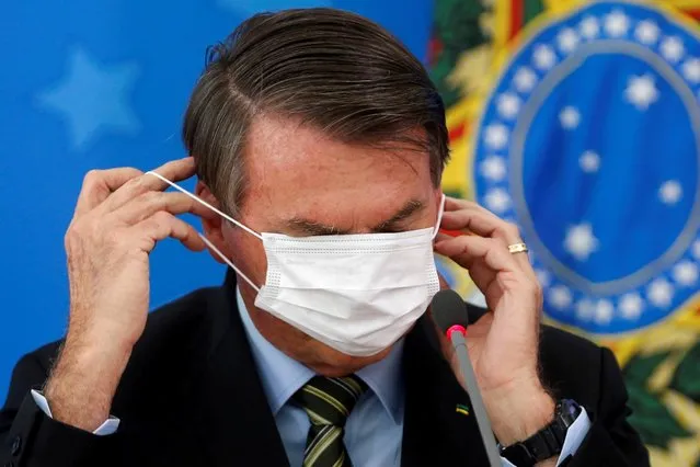Brazil's President Jair Bolsonaro adjusts his protective face mask during a news conference to announce measures to curb the spread of the coronavirus disease (COVID-19) in Brasilia, Brazil on March 18, 2020. (Photo by Adriano Machado/Reuters)
