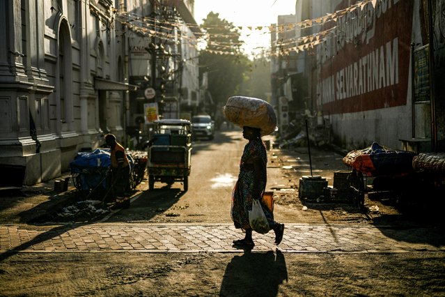 A woman walks across a street early morning in Chennai on October 30, 2025. (Photo by R. Satish Babu/AFP Photo)