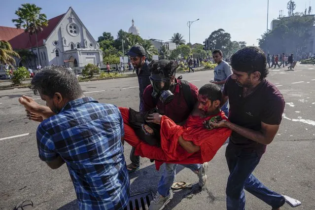 Members of Sri Lankan opposition political party National People's Power carry an injured Buddhist monk  during a clash with police in Colombo, Sri Lanka, Sunday, February 26, 2023. The opposition supporters were protesting over a decision to postpone local elections after the government said it cannot finance the same because of the country's crippling economic crisis. (Photo by Eranga Jayawardena/AP Photo)