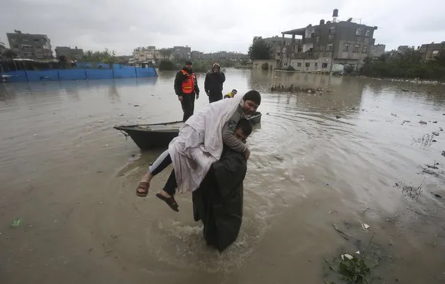 A member of Palestinian Civil Defence carries a boy after he was evacuated from his family's house which was flooded by heavy rain in Rafah in the southern Gaza Strip January 9, 2015. (Photo by Ibraheem Abu Mustafa/Reuters)