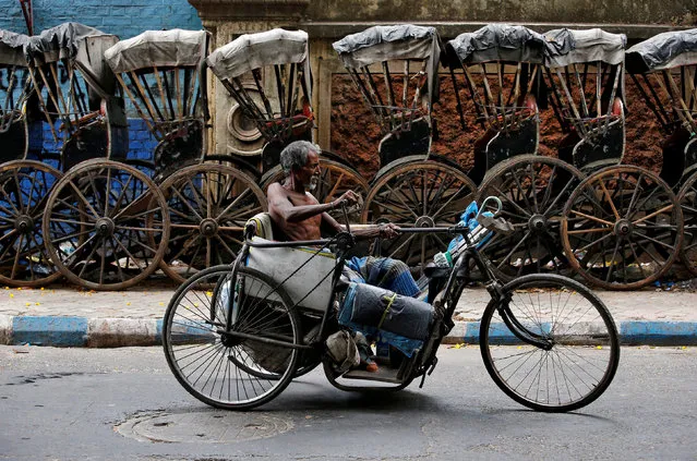 A disabled man paddles his tricycle as he moves past a row of parked hand-pulled rickshaws in Kolkata, India, May 10, 2018. (Photo by Rupak De Chowdhuri/Reuters)