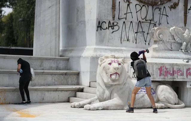Protestors angry at the police attack the monument to Mexico's first indigenous president, Benito Juárez, at the Alameda Central park as they destroy storefronts and bus stops in Mexico City, Monday, June 8, 2020. The graffiti reads in Spanish “The police kill”. Following the death of Mexican man Giovanni Lopez, who was allegedly beaten to death while in police custody in Jalisco in May, anarchist protesters who are known for their violent tactics smashed storefronts, looted businesses, and sprayed anti-police graffiti on monuments. (Photo by Rebecca Blackwell/AP Photo)