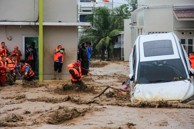 Rescuers wade through flood waters by holding a rope in their effort to evacuate residents who are trapped at their houses in Padang, West Sumatra province on November 27, 2025. (Photo by Rezan Soleh/AFP Photo)