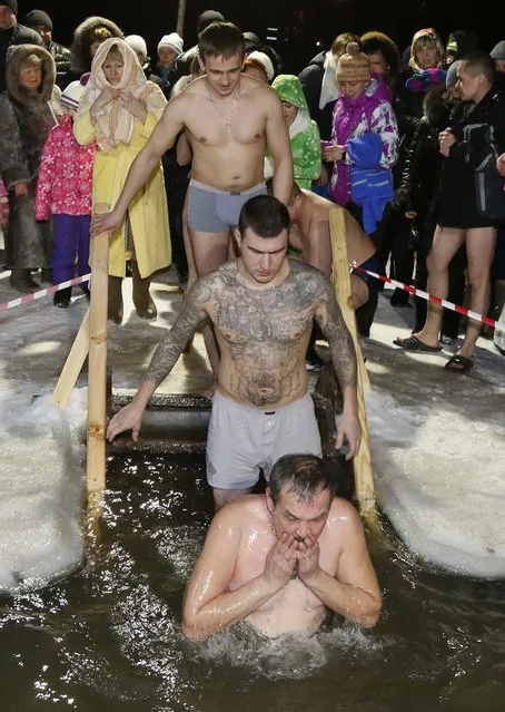 People immerse themselves in an ice hole in the Chulym river, with the air temperature at about minus 12 degrees Celsius (10.4 degrees Fahrenheit), during celebrations for the Russian Orthodox Epiphany outside of the town of Nazarovo, Krasnoyarsk region January 19, 2015. (Photo by Ilya Naymushin/Reuters)