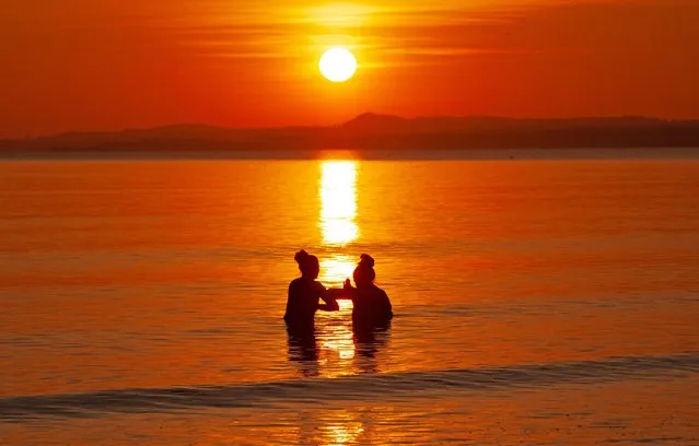 Two female wild swimmers enjoy a dip at dawn in the Firth of Forth in Edinburgh, Scotland on April 4, 2023. (Photo by Archwhite/Alamy Live News)