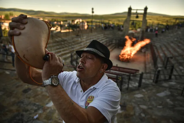A man drinks from wineskin before walking on the burning embers during the night of San Juan in San Pedro Manrique, northern Spain, Saturday, June 23, 2018. The night of San Juan, which welcomes the summer season, is an ancient tradition celebrated every year in various towns in Spain. (Photo by Alvaro Barrientos/AP Photo)