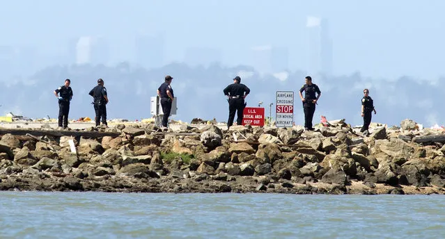 Investigators comb the end of a runway at San Francisco International Airport following the crash of Asiana Flight 214 on Saturday, July 6, 2013, in San Francisco. (Photo by Noah Berger/AP Photo)