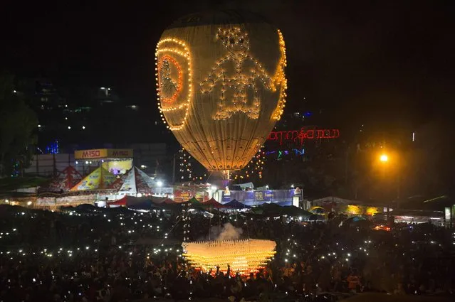 This picture taken on November 11, 2016 shows participants releasing a hot- air balloon during the Tazaungdaing Lighting Festival at Taunggyi in Myanmar' s northeastern Shan State. The skies of central Myanmar were set ablaze this week with the beginning of the Taunggyi fire balloon festival, one of the most beautiful and dangerous celebrations in Asia. Brightly coloured balloons with hundreds of homemade fireworks woven into their frames are sent soaring into the night sky, showering down cascades of sparks onto adoring crowds. (Photo by Ye Aung Thu/AFP Photo)
