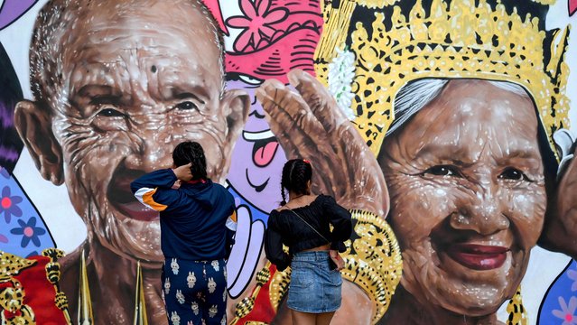 Women look at a billboard displaying images of elderly people for New Year celebrations in Phnom Penh on January 2, 2025. (Photo by Tang Chhin Sothy/AFP Photo)