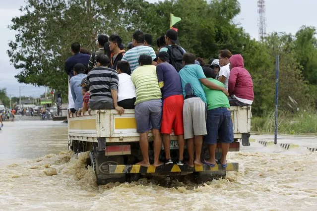 People ride on a delivery truck to cross a flooded road after heavy rain at Candaba town, Pampanga province, north of Manila, December 17, 2015. (Photo by Czar Dancel/Reuters)