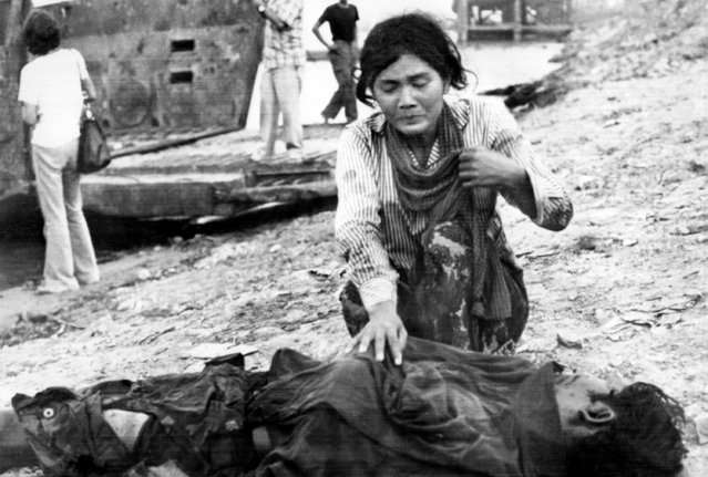 A woman cries next to a dead body, 17 April 1975 in Phnom Penh, after the Khmer Rouge enter the Cambodian capital and establish government of Democratic Kampuchea (DK). (Photo by Claude Juvenal/AFP Photo)