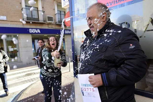 A woman sprays champagne over a man who won the second prize of El Gordo Christmas lottery going to the ticket number 12.775 in Mora, province of Toledo, Spain, 22 December 2015.  The traditional Spanish Christmas Lottery “El Gordo” (The Fat One) will share some 2.24 billion euros in prizes, 640 millions of them going for the Jackpot with 400,000 euros per ticket. The second prize is worth in 1.250 million euro, the third one is worth 500,000 euro, the fourth one 200,000 euro and the fifth one 60,000 euro. (Photo by Ismael Herrero/EPA)