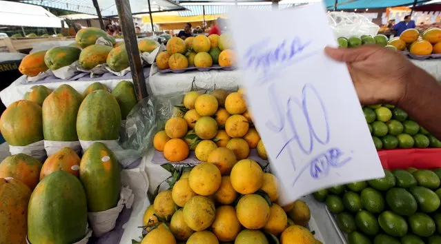 A vendor holds a placard with the price of papaya in a street market in Sao Paulo,December 9, 2015. Brazil's annual inflation rate climbed above 10 percent to a 12-year high in November, which was more than expected and may force tighter monetary policy despite a severe recession. Consumer prices measured by the benchmark IPCA index rose 10.48 percent in the 12 months through November, up from an increase of 9.93 percent in October and above a Reuters poll forecast of 10.41 percent, government statistics agency IBGE said on Wednesday. (Photo by Paulo Whitaker/Reuters)