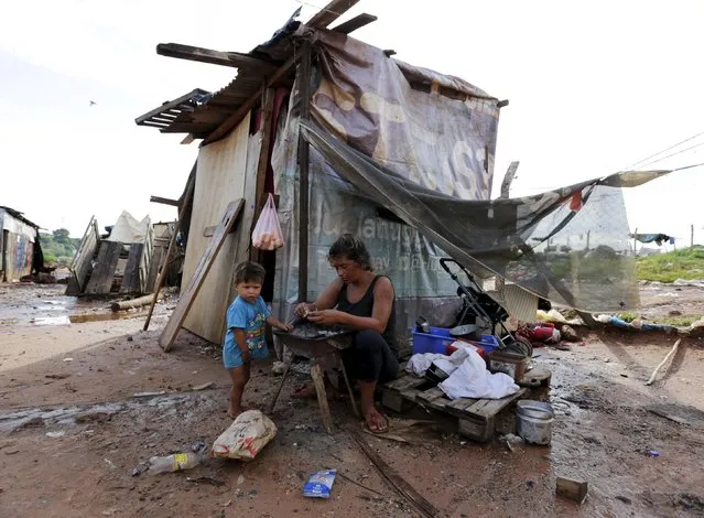 A woman sits next to a makeshift shelter with her son in Asuncion, December 27, 2015. (Photo by Jorge Adorno/Reuters)