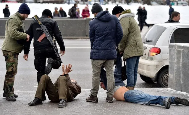 A patrol made up of members of a Ukrainian volunteers battalion and policemen arrest two men on Independence Square in Kiev on February 9, 2015, who allegedly arrived from Donetsk and are suspected of participating in seperatist activities and organizing terrorist attacks in the Ukrainian capital. (Photo by Sergei Supinsky/AFP Photo)