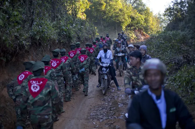 In this January 12, 2015 photo, men on motorcycles watch officers of the Ta’ang National Liberation army, who gathered in the steep, mountainside village of Mar Wong in northern Shan state, Myanmar to celebrate the 52nd anniversary of their insurrection against successive governments. (Photo by Gemunu Amarasinghe/AP Photo)