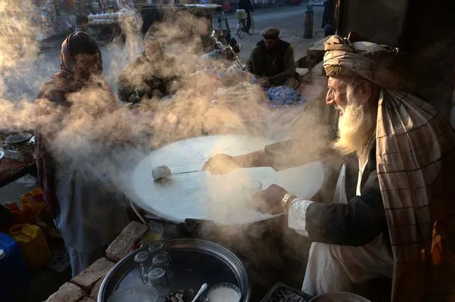 An Afghan shopkeeper boils milk as he waits for customers at dawn in Jalalabad in Nangarhar province on January 16, 2015. Afghanistan's economy has improved significantly since the fall of the Taliban regime in 2001 largely because of the infusion of international assistance. Despite significant improvement in the last decade the country is still extremely poor and remains highly dependent on foreign aid. (Photo by Noorullah Shirzada/AFP Photo)