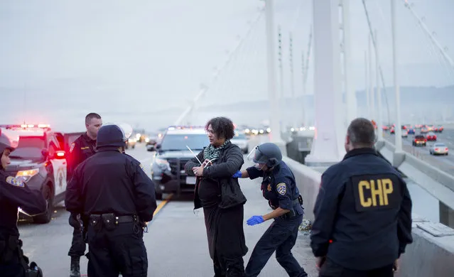 A California Highway Patrol officer detains a protester on the San Francisco-Oakland Bay Bridge, Monday, January 18, 2016, in San Francisco. A group of protesters from the group Black Lives Matter caused the shutdown of one side of the bridge in a police-brutality protest tied to the Rev. Martin Luther King Jr. holiday. (Photo by Noah Berger/AP Photo)