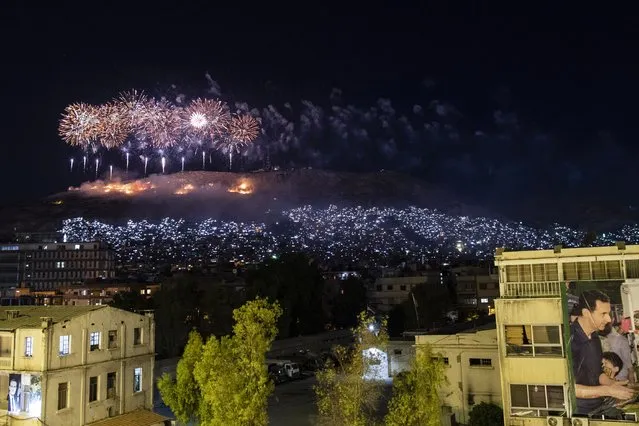 Fireworks explode over Qasioun Mountain as Syrian President Bashar Assad supporters celebrate Assad's presidential re-election, in Damascus, Syria, Thursday, May 27, 2021. Syrian President Bashar Assad was re-elected in a landslide, officials said Thursday, ushering in a fourth seven-year term. (Photo by Hassan Ammar/AP Photo)