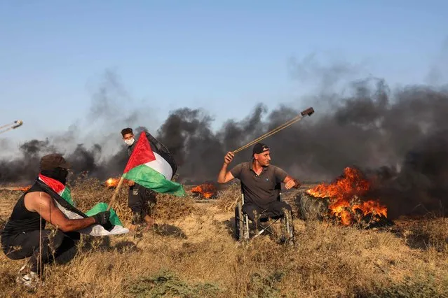A Palestinian demonstrator uses a slingshot to hurl rocks towards Israeli soldiers during a rally near the Israel-Gaza border fence east of Gaza City on September 22, 2023. (Photo by Mohammed Abed/AFP Photo)