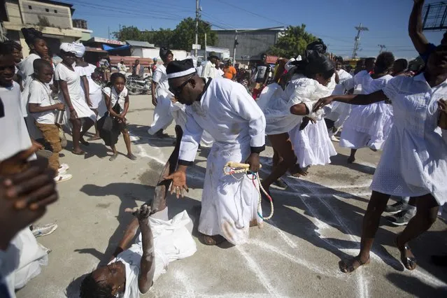 In this November 1, 2018 photo, voodoo believers who are supposed to be possessed with Gede spirit perform rituals in the middle of the street during the annual Voodoo festival Fete Gede at Cite Soleil Cemetery in Port-au-Prince, Haiti. Along the celebration, which starts on October and has its climax on November 1st and 2, the believers wear the distinctive clothes of their Loas or Gedes, the creol generic name for the spirits. (Photo by Dieu Nalio Chery/AP Photo)