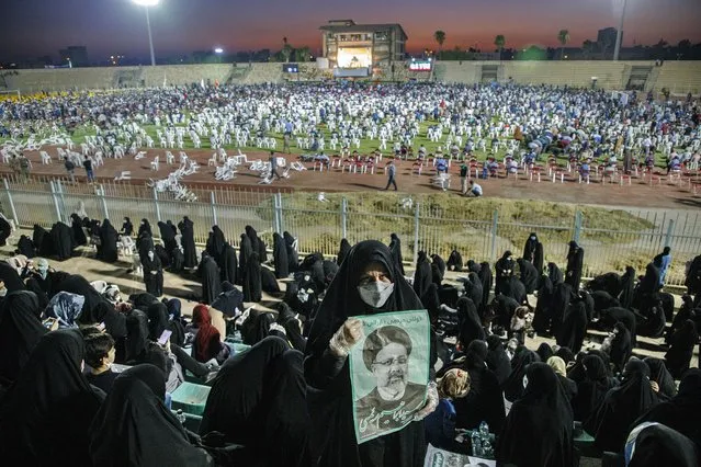 In this Wednesday, June 9, 2021, photo, a supporter of the presidential candidate Ebrahim Raisi, currently judiciary chief, hold posters of him during a campaign rally at the Takhti Stadium in Ahvaz, Iran. Around 5,000 of people have gathered in a football stadium in southeastern city of Ahvaz to support the Iranian hard-line presidential candidate, Iranian media reported. (Photo by Amin Nazari/ISNA via AP Photo)