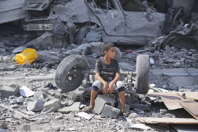 A Palestinian boy sits on the rubble of his building destroyed in an Israeli airstrike in Nuseirat camp in the central Gaza Strip on Monday, October 16, 2023. (Photo by Hatem Moussa/AP Photo)
