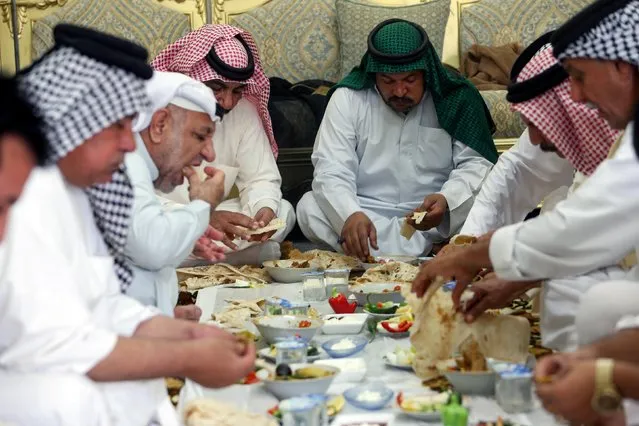 Iraqi men eat traditional “Masmouta”, a Basra fish meal, during Eid al-Fitr in Basra, Iraq, May 14, 2021. (Photo by Essam al-Sudani/Reuters)
